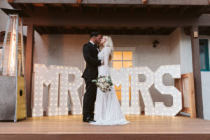 Bride and Groom Kissing in Front of Mr and Mrs Marquee Lighting
